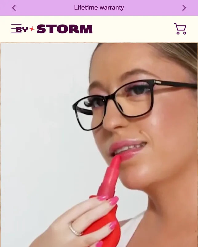 ByStorm’s home page on a phone: the ‘By Storm’ wordmark above a video still of a woman in glasses holding a lipstick in a red grip.
